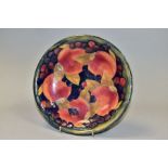 A MOORCROFT POTTERY SHALLOW BOWL DECORATED IN THE POMEGRANATE DESIGN ON A MOTTLED GREEN / BLUE