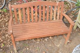 A BROWN PAINTED WOODEN SLATTED GARDEN BENCH, width 128cm x depth 58cm