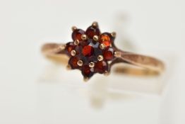 A 9CT GOLD GARNET CLUSTER RING, designed as a circular shape stepped garnet cluster, with tapered