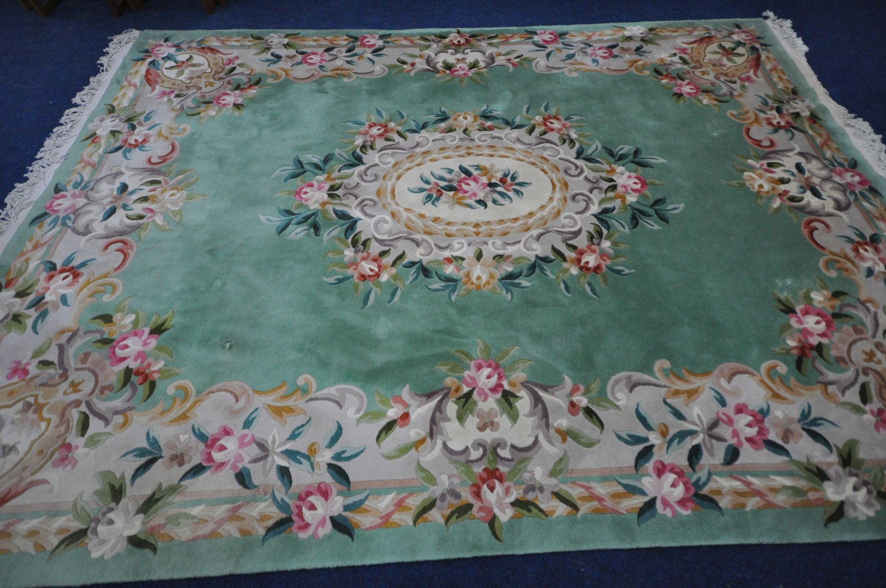 A LARGE CHINESE GREEN GROUND WOOLLEN RUG, with foliate design to centre and border, length 370cm x