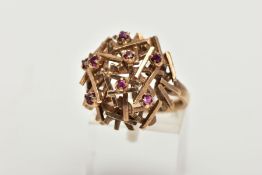 A 9CT GOLD ABSTRACT DRESS RING, a dome of bars nested together set with eight circular cut rubies,