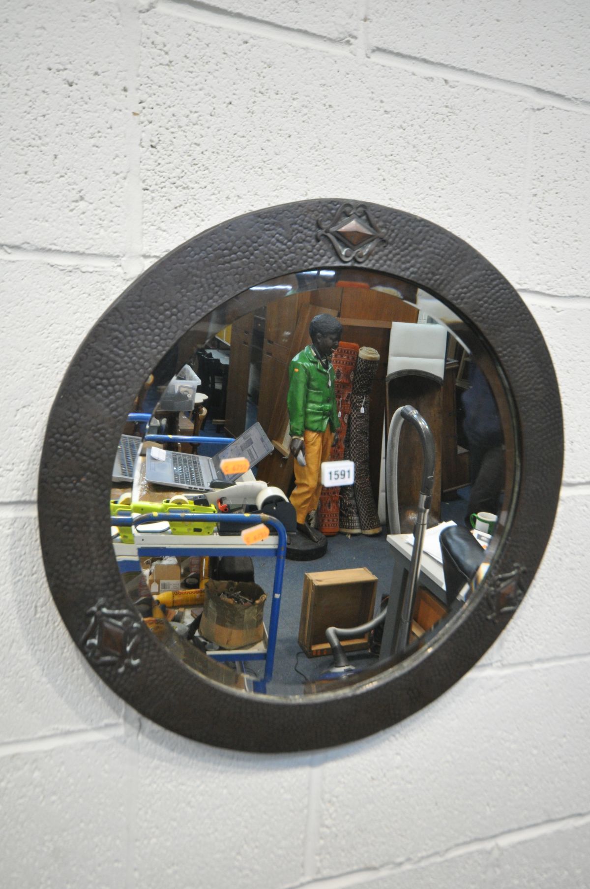 AN ARTS AND CRAFTS BEATEN COPPER CIRCULAR WALL MIRROR, with a bevelled edge plate, 56cm diameter (