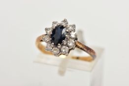 A YELLOW METAL SAPPHIRE AND DIAMOND CLUSTER RING, centring on an oval cut deep blue sapphire, within