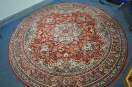 A LARGE CIRCULAR RED GROUND RUG, with a foliate design, 240cm diameter, along with two Chinese rugs,