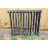 A VICTORIAN BLACK PAINTED CAST IRON RADIATOR, with Nut badged ideal, width 80cm, height from feet