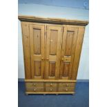 A LARGE PINE TRIPLE DOOR WARDROBE, loose cornice, with four long drawers flanking two short drawers,