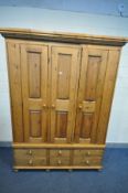 A LARGE PINE TRIPLE DOOR WARDROBE, loose cornice, with four long drawers flanking two short drawers,