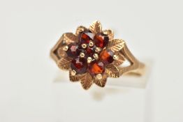 A 9CT GOLD GARNET FLORAL CLUSTER RING, designed as a circular shape stepped garnet cluster, with