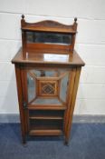 AN EDWARDIAN WALNUT MUSIC CABINET, with a mirrored raised back with a shelf, a single door with four