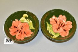 A PAIR OF MOORCROFT POTTERY SMALL FOOTED BOWLS, coral hibiscus on a green ground, impressed marks,