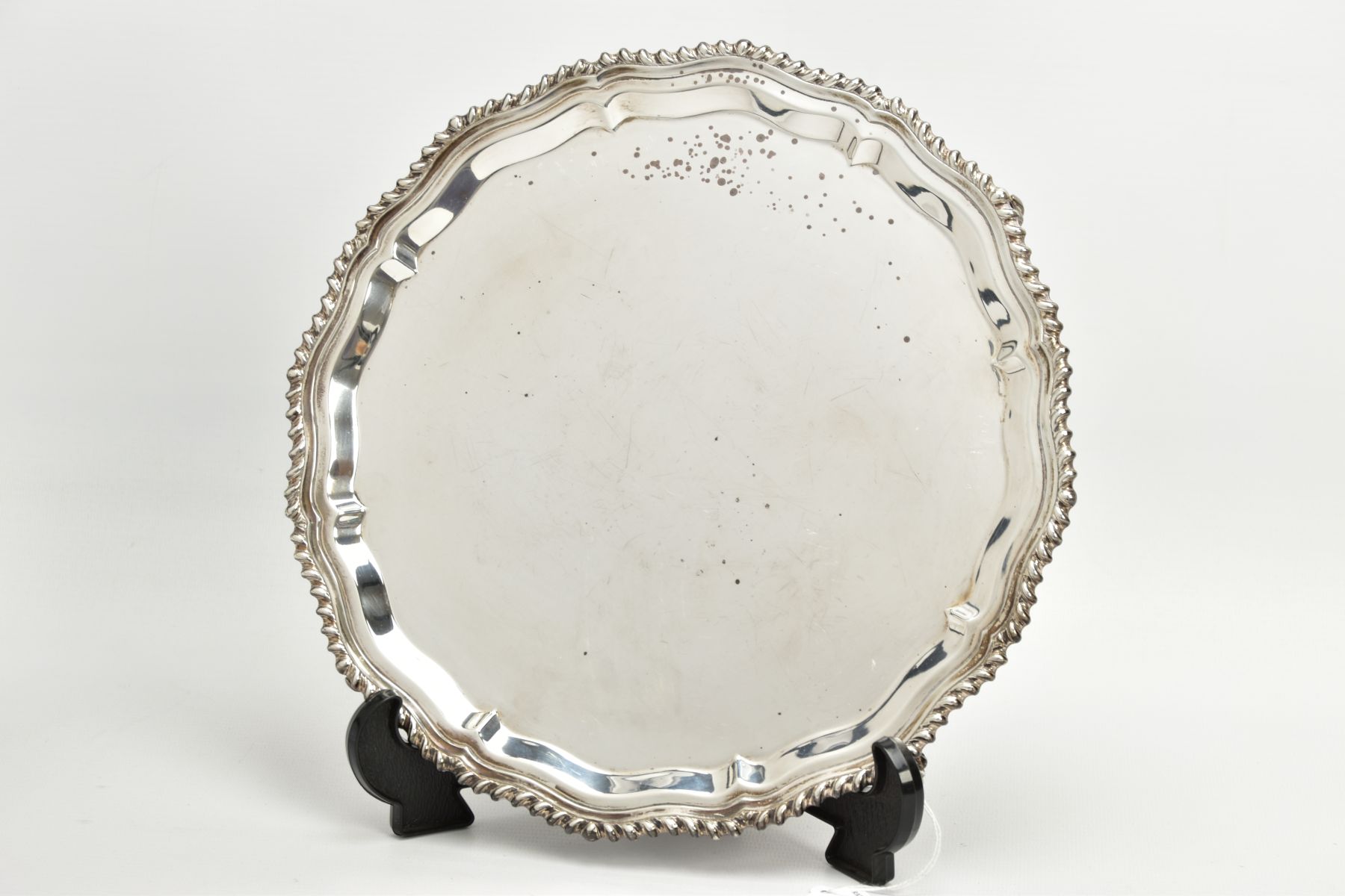 A SILVER SALVER, circular wavy form, gadrooned rim, raised on four scroll feet, hallmarked 'J B