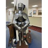 A NEAR LIFE SIZE REPLICA METAL SUIT OF ARMOUR WITH VISOR, mounted on a wooden stand, overall