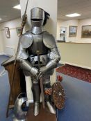 A NEAR LIFE SIZE REPLICA METAL SUIT OF ARMOUR WITH VISOR, mounted on a wooden stand, overall