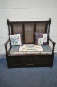 AN EARLY 20TH CENTURY OAK HALL SETTLE, with bergère back, barley twist supports, open armrests and