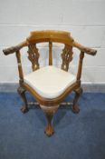 A REPRODUCTION HARDWOOD CORNER CHAIR, with mythical creatures to armrests, pierced splats, cream