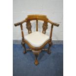 A REPRODUCTION HARDWOOD CORNER CHAIR, with mythical creatures to armrests, pierced splats, cream