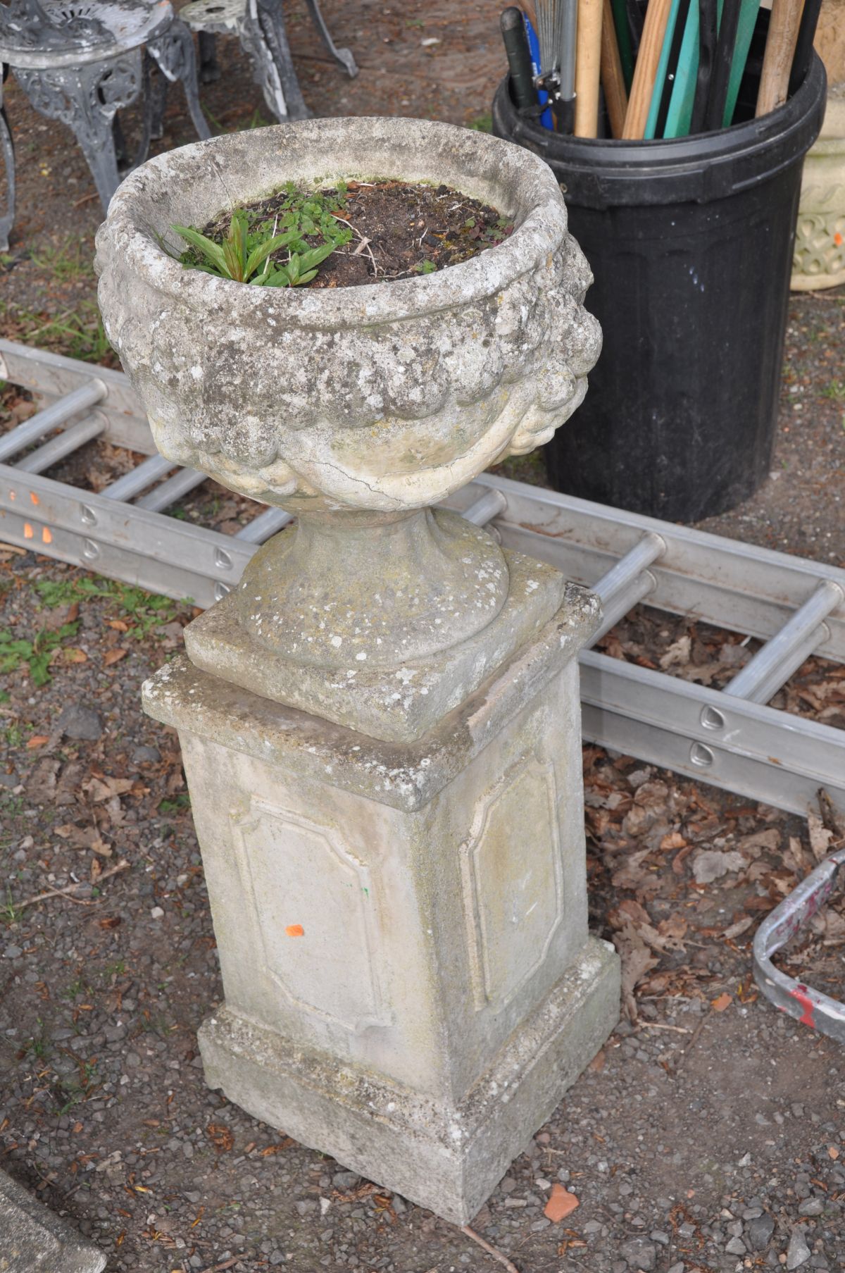 A COMPOSITE CIRCULAR URN, with decorated sides, on a separate square plinth, height to plinth