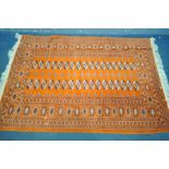 A 20TH CENTURY TEKKE WOOLLEN RUG, thirty four medallions withing an orange field, and a multi