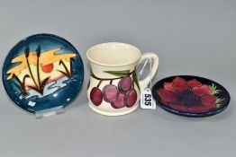 A MOORCROFT POTTERY MUG DECORATED WITH PLUMS ON A CREAM GROUND, height 8.5cm and two circular pin