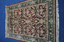 A MID TO LATE 20TH CENTURY HAND KNOTTED WOOLEN RUG, with foliate design between a red field, and a