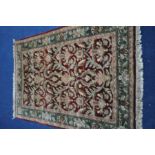 A MID TO LATE 20TH CENTURY HAND KNOTTED WOOLEN RUG, with foliate design between a red field, and a