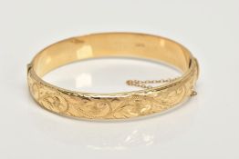 A 9CT GOLD BANGLE, a hollow domed hinged bangle, engraved with a scrolling foliage design, fitted