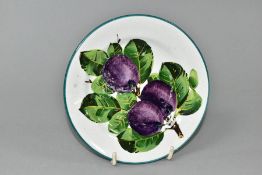 A WEMYSS TEA PLATE PAINTED WITH PURPLE PLUMS ON A SECTION OF BRANCH, retailed by T. Goode & Co,