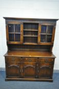 A REPRODUCTION OAK DRESSER, the top with double glazed cupboard door flanking an open shelf section,