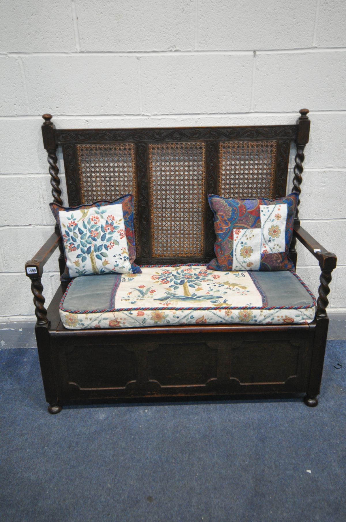 AN EARLY 20TH CENTURY OAK HALL SETTLE, with bergère back, barley twist supports, open armrests and