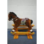 A FABRIC ROCKING HORSE, on a beech trestle stand, length 101cm x height 106cm