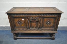 A REPRODUCTION JACOBEAN STYLE OAK COFFER, with an arrangement of panels, on turned legs, united by a