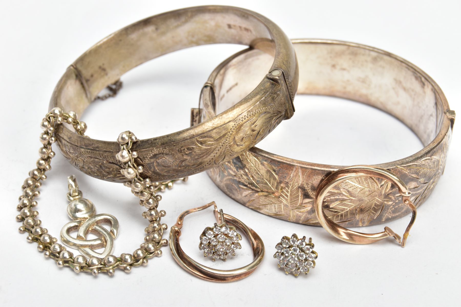 TWO SILVER BANGLES, EARRINGS AND A BRACELET, to include a wide hinged bangle decorated with a floral