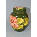 A MOORCROFT POTTERY GINGER JAR AND COVER DECORATED IN FLORAL HIBISCUS ON A GREEN GROUND, the cover