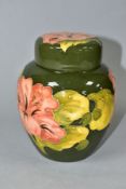 A MOORCROFT POTTERY GINGER JAR AND COVER DECORATED IN FLORAL HIBISCUS ON A GREEN GROUND, the cover