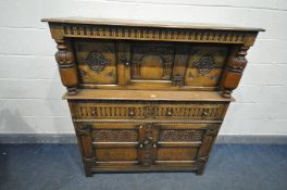 A REPRODUCTION OAK COURT CUPBOARD, the canopy with a single carved door, with twin acorn supports,