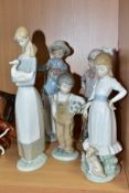 FIVE NAO PORCELAIN FIGURINES, comprising a girl with a hoop, two children with puppies, a boy with a