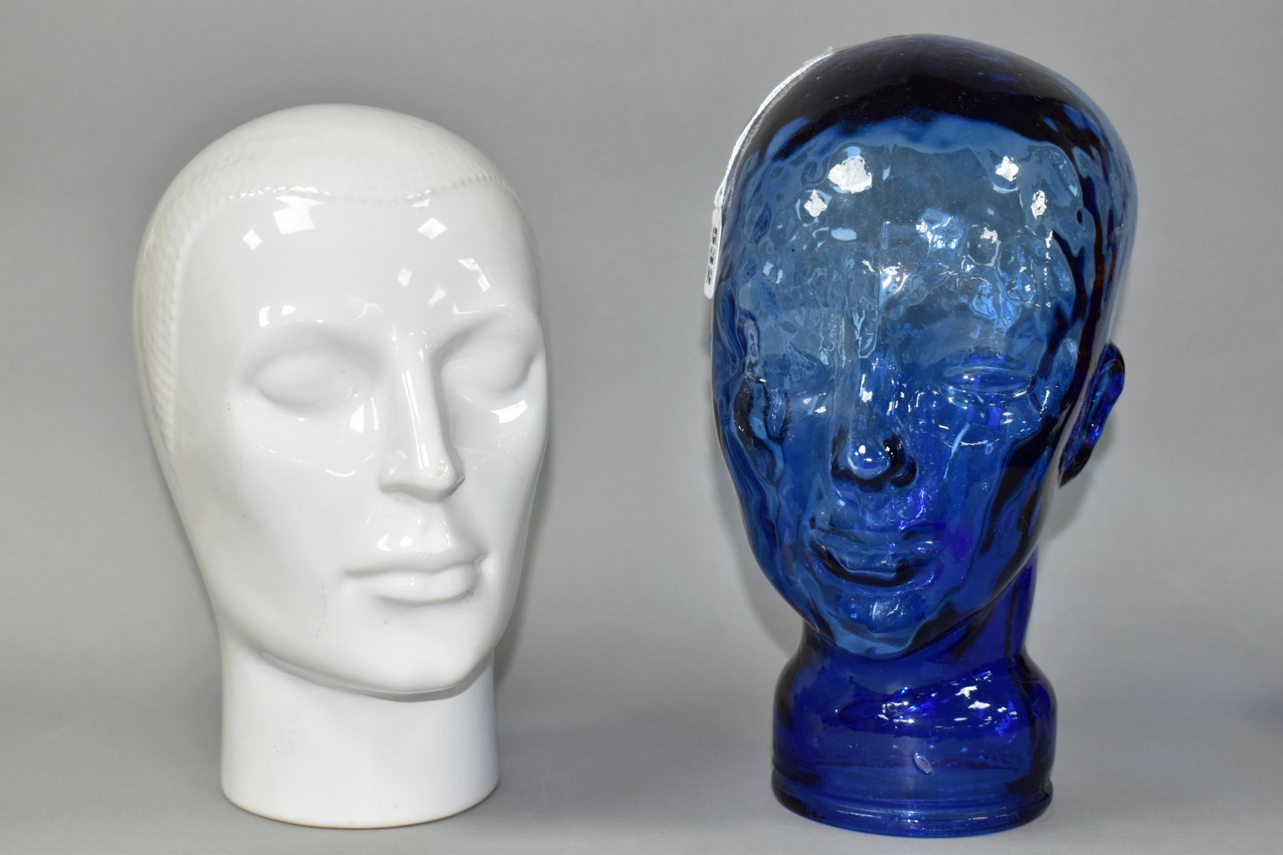 TWO DECORATIVE DISPLAY HEADS IN BLUE GLASS AND WHITE GLAZED CERAMIC, heights 30cm and 27cm (2) (