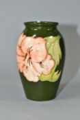 A MOORCROFT POTTERY BALUSTER VASE DECORATED WITH CORAL HIBISCUS ON A GREEN GROUND, impressed