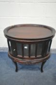A REPRODUCTION MAHOGANY OVAL DRINKS CABINET, with a removable tray, bevelled glass panels, single