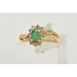 A YELLOW METAL EMERALD AND DIAMOND RING, an oval cut emerald prong set within a surround of twelve