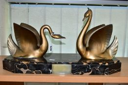 AN ART DECO STYLE SCULPTURE OF TWO GILT METAL SWANS ON A SHAPED RECTANGULAR MARBLE PLINTH, after