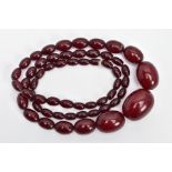 A CHERRY AMBER BAKELITE BEAD NECKLACE, a single row of graduated oval beads, fifty-seven in total,