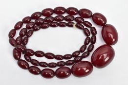 A CHERRY AMBER BAKELITE BEAD NECKLACE, a single row of graduated oval beads, fifty-seven in total,