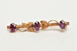 A 9CT GOLD BAR BROOCH, a yellow gold foliage bar brooch, set with three oval cut pink stones,