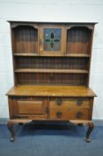 AN ARTS AND CRAFTS OAK DRESSER, the top with coloured glass panel door, surrounded by shelves,