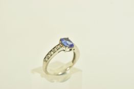 A 9CT GOLD TANZANITE AND COLOURLESS GEM DRESS RING, the oval tanzanite, to the circular colourless