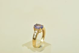 A 9CT GOLD TANZANITE AND COLOURLESS GEM DRESS RING, the oval tanzanite, to the circular colourless