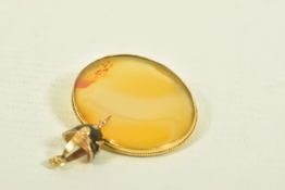 A YELLOW METAL BROOCH AND A CHARM, the first an oval shape carnelian brooch within a rope twist