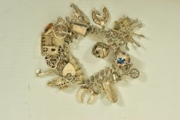 A WHITE METAL CHARM BRACELET, comprising approximately twenty plus various charms to include a fish,