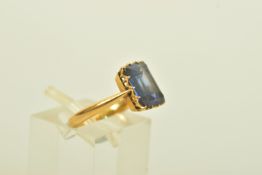 AN EARLY 20TH CENTURY YELLOW METAL SYNTHETIC SAPPHIRE SINGLE STONE RING, set with a rectangular step